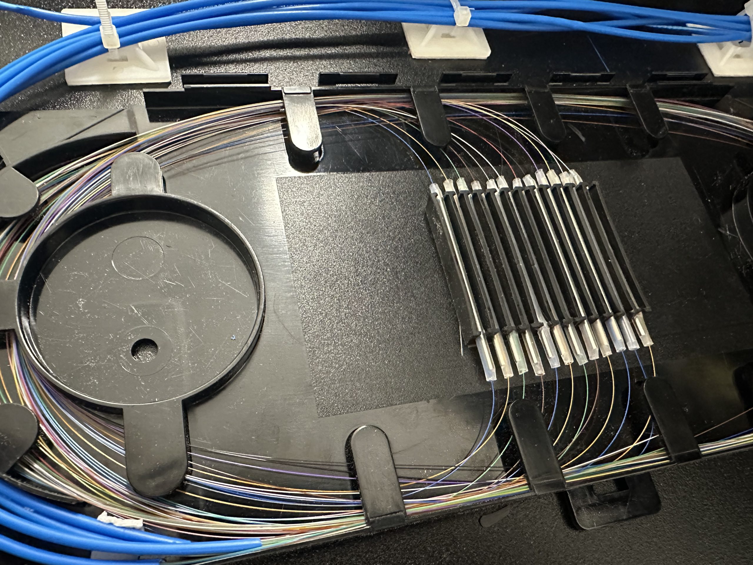 Peinado meticuloso y organización de hilos de fibra óptica en charola de empalme splice tray