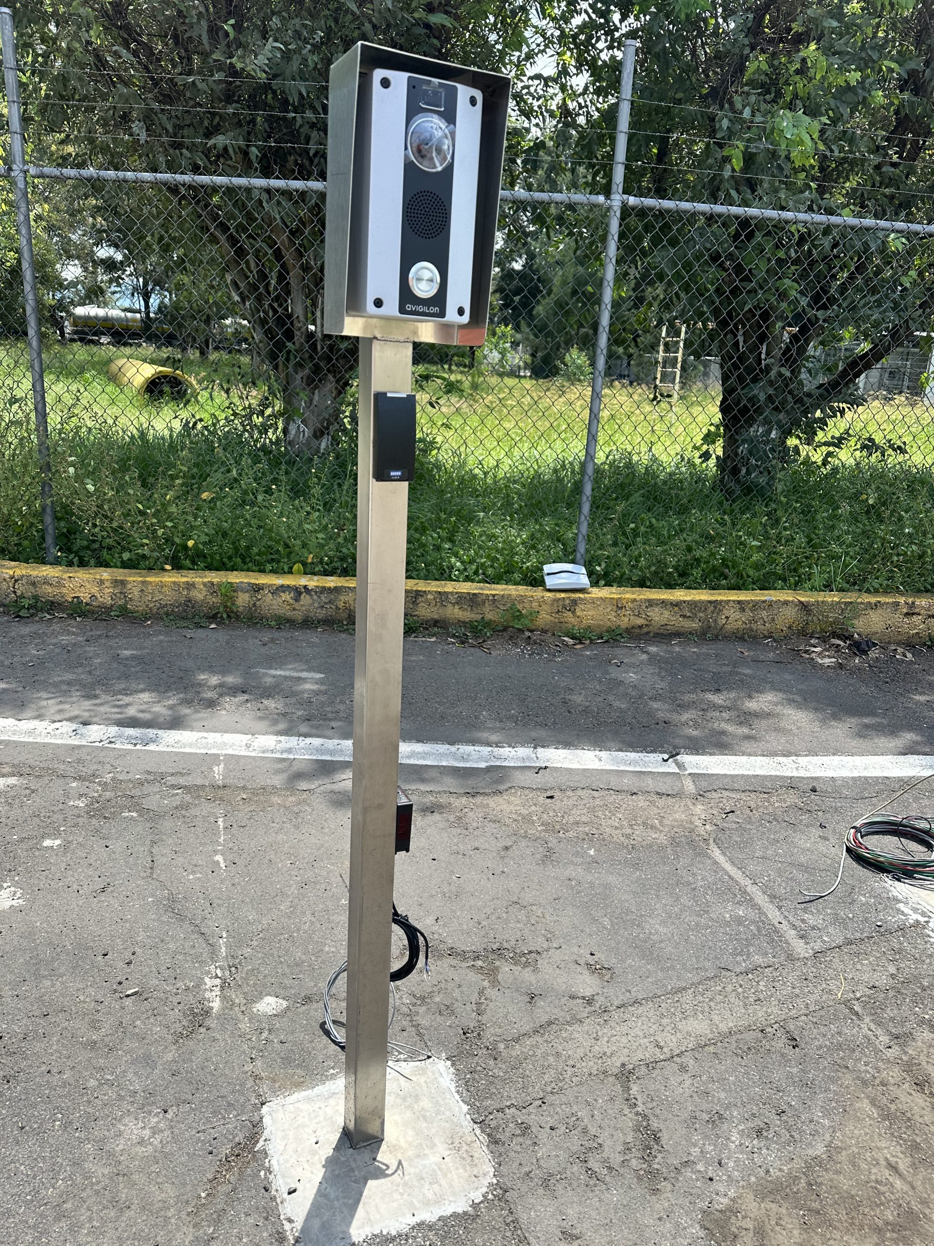 Poste de control de acceso perimetral para validación vehicular y botón de emergencia en patio de maniobra